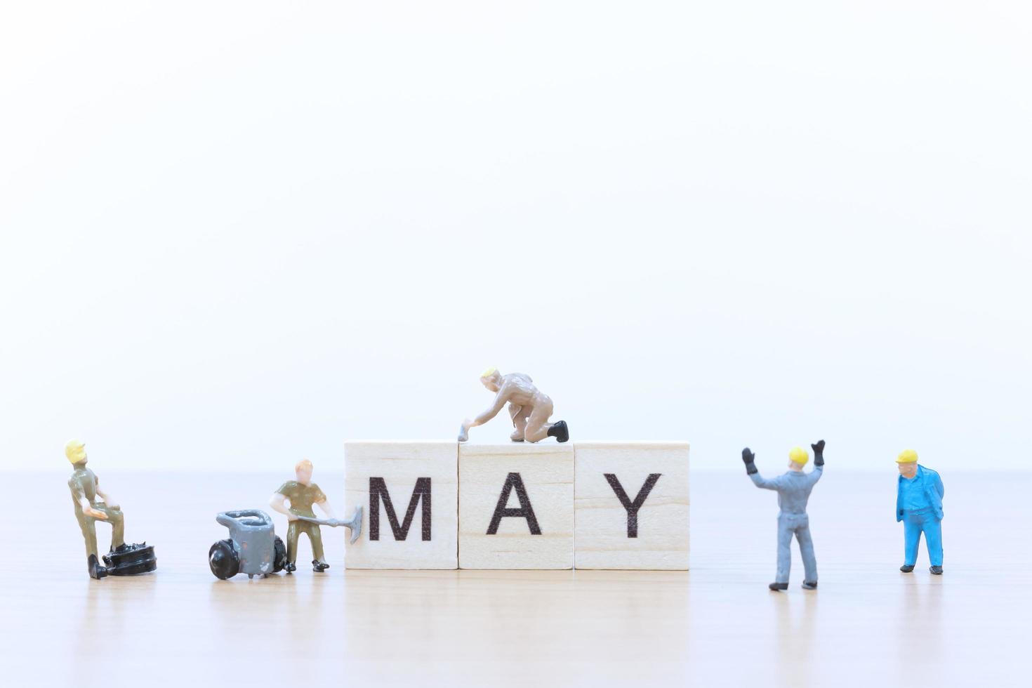 Gente en miniatura trabajando en bloques de madera con la palabra puede sobre un piso de madera foto