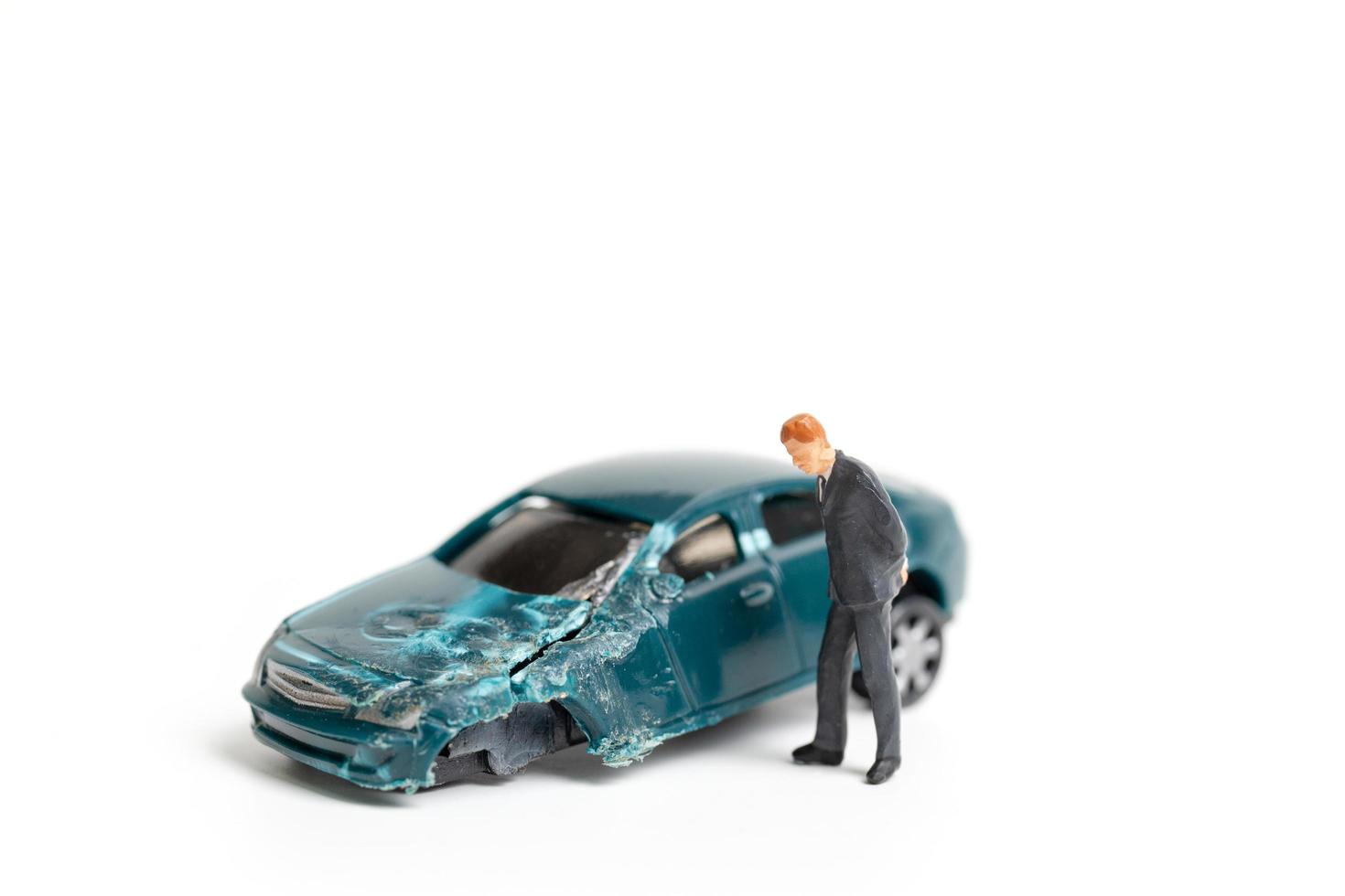 Persona en miniatura en la escena de un accidente automovilístico, accidente automovilístico sobre un fondo blanco, concepto de conducción segura foto