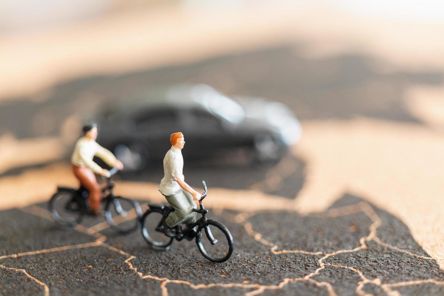 Viajeros en miniatura con bicicletas sobre un fondo de mapa del mundo foto