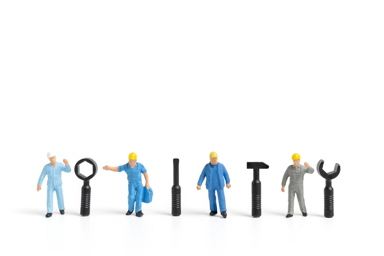 Miniature workers with tool supplies on a white background, construction concept photo