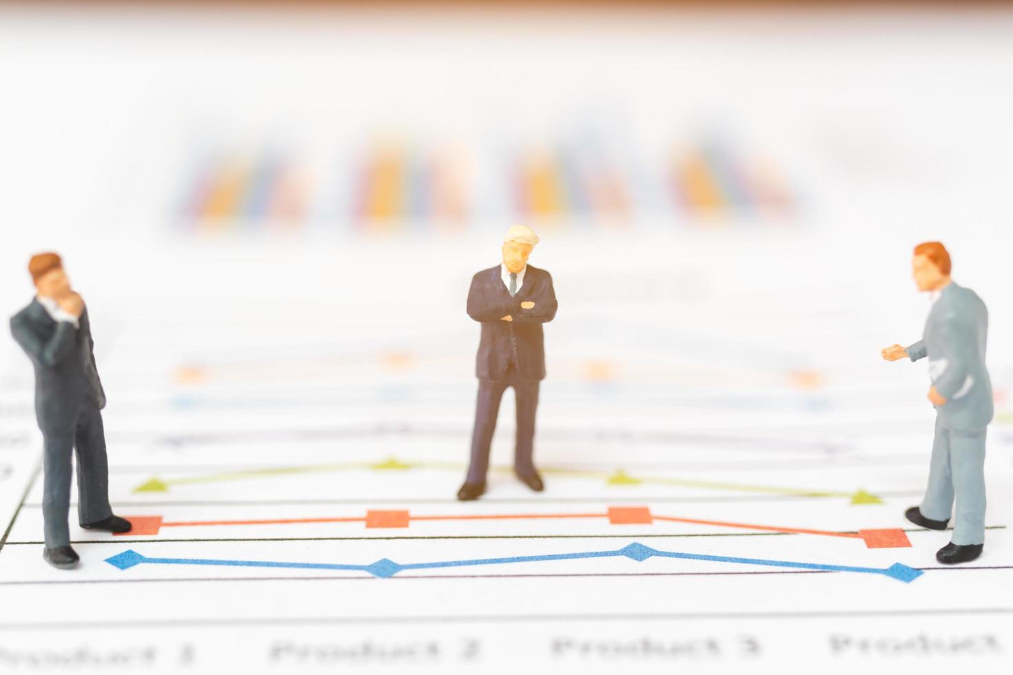 Miniature businessmen standing on charts photo