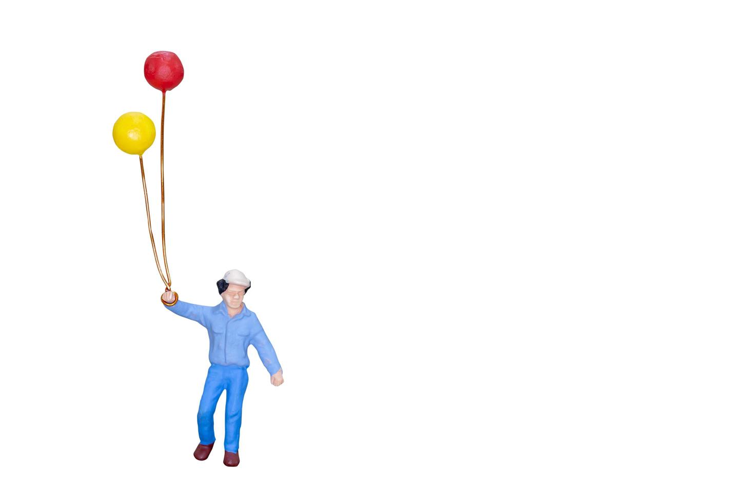 Miniature person holding balloons isolated on a white background photo