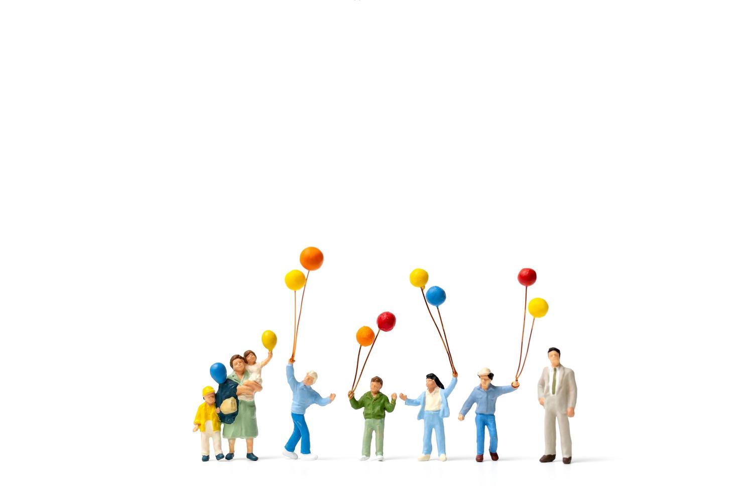 Miniature people holding balloons isolated on a white background photo