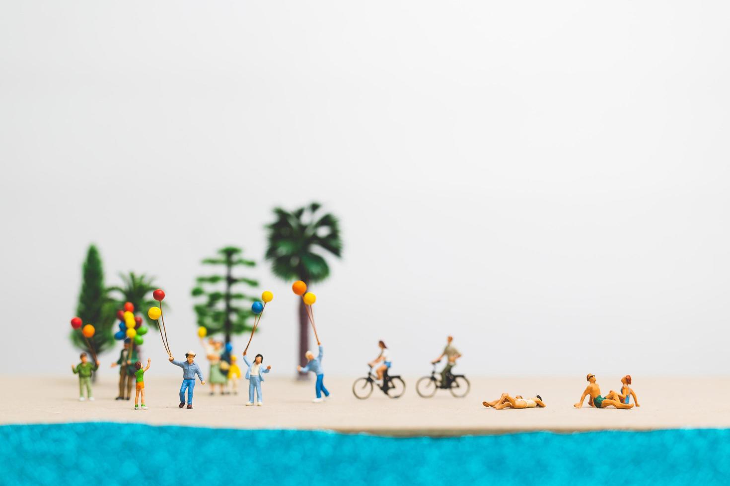 Gente en miniatura disfrutando de las vacaciones de verano en la playa. foto