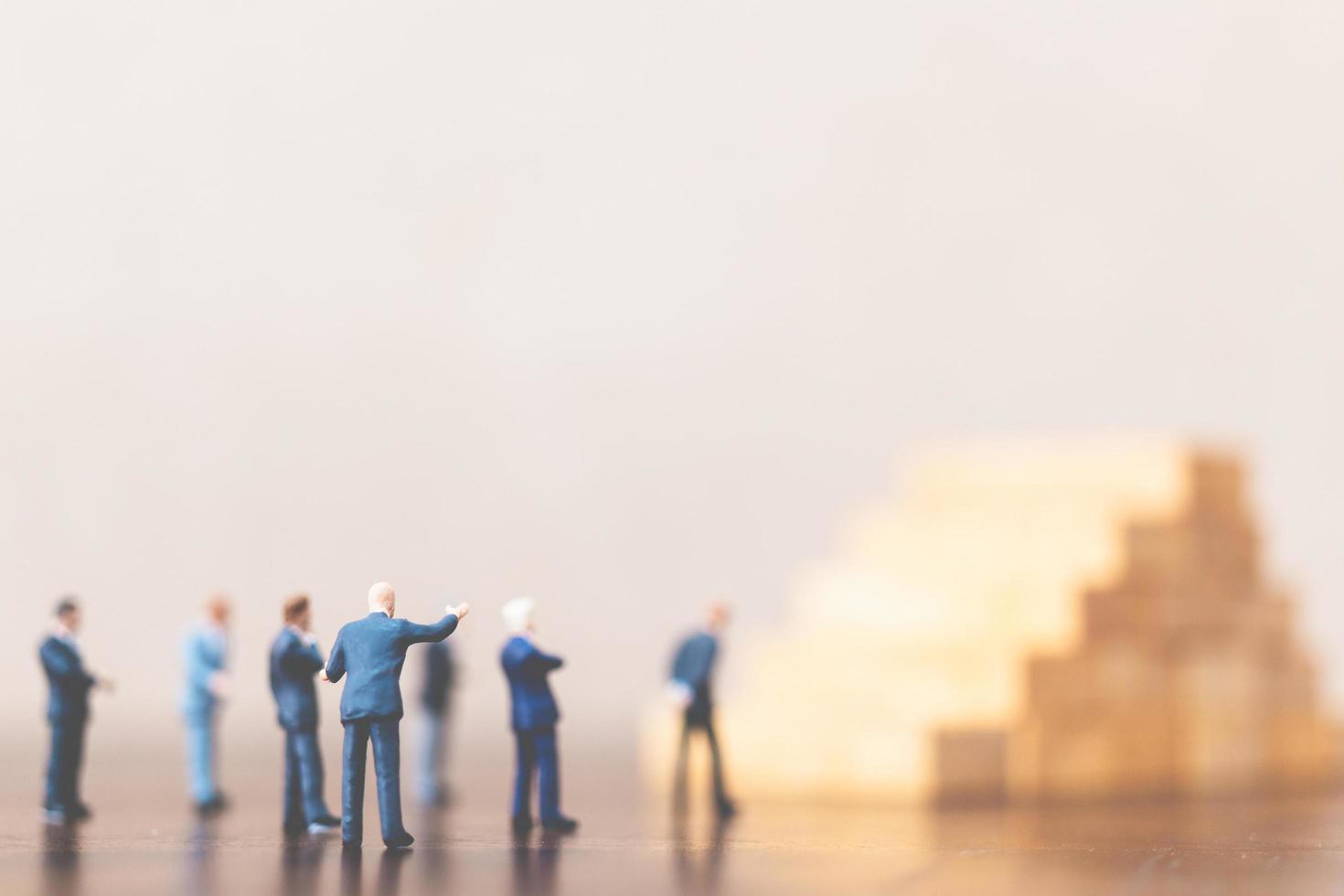 Miniature businessmen standing on a wooden block, successful business leader and teamwork concept photo