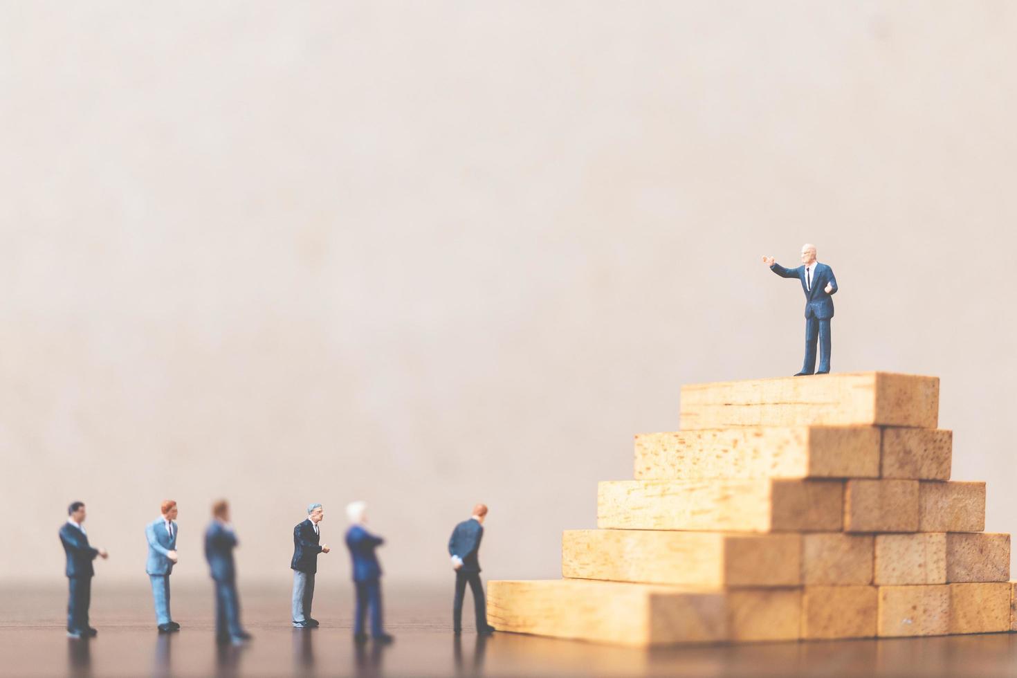 Miniature businessmen standing on a wooden block, successful business leader and teamwork concept photo