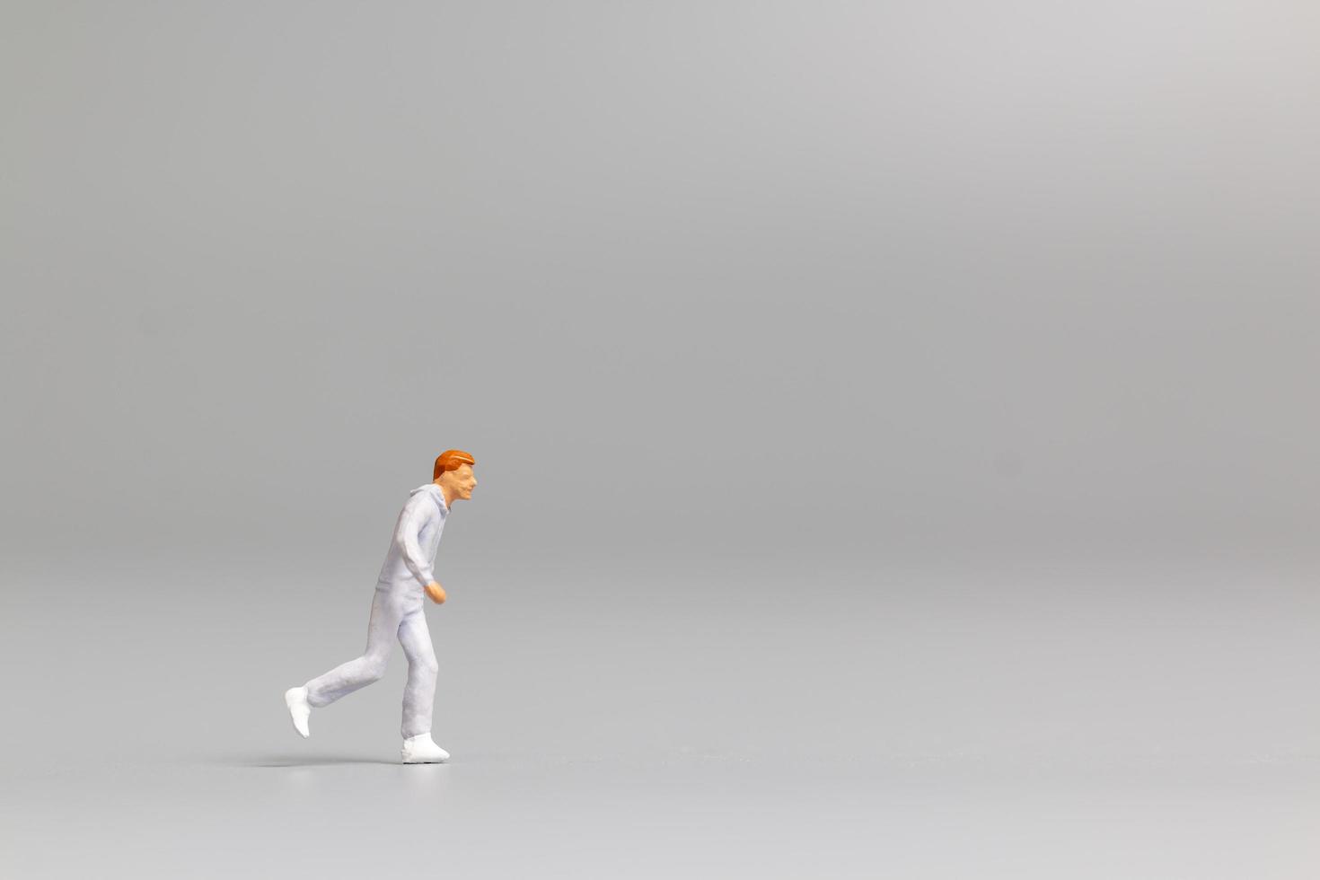 Persona en miniatura corriendo sobre un fondo gris foto