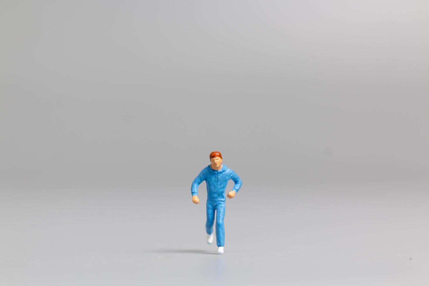 Miniature person running on a gray background photo