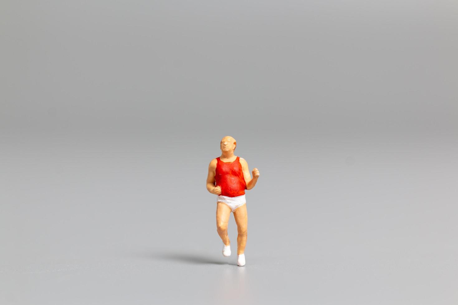 Miniature person running on a gray background photo