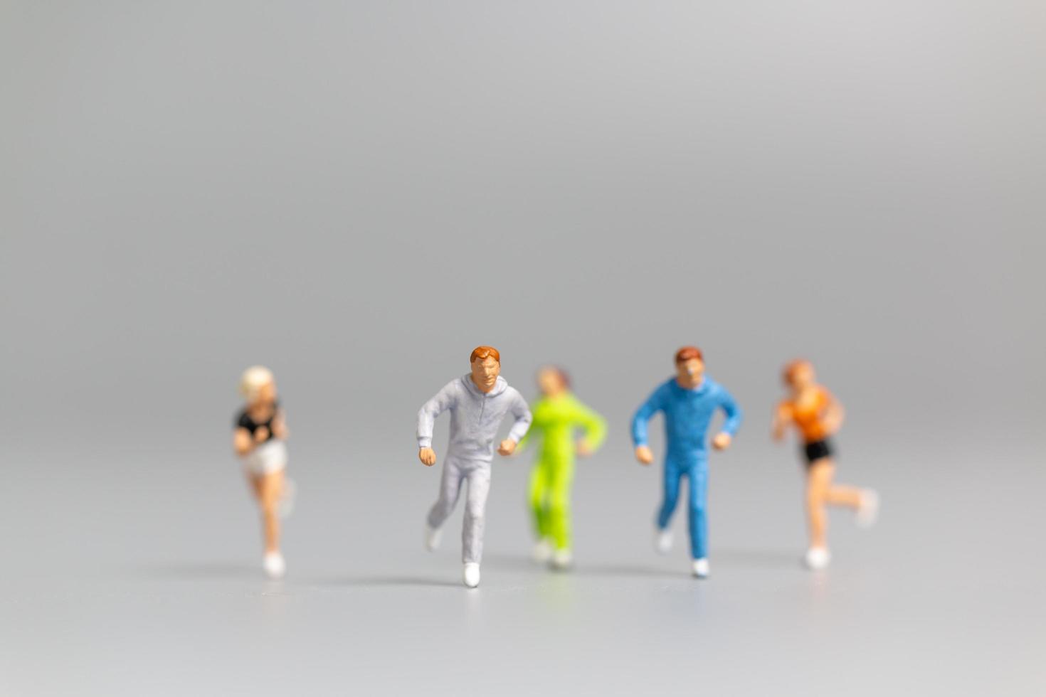 Miniature people running on a gray background photo