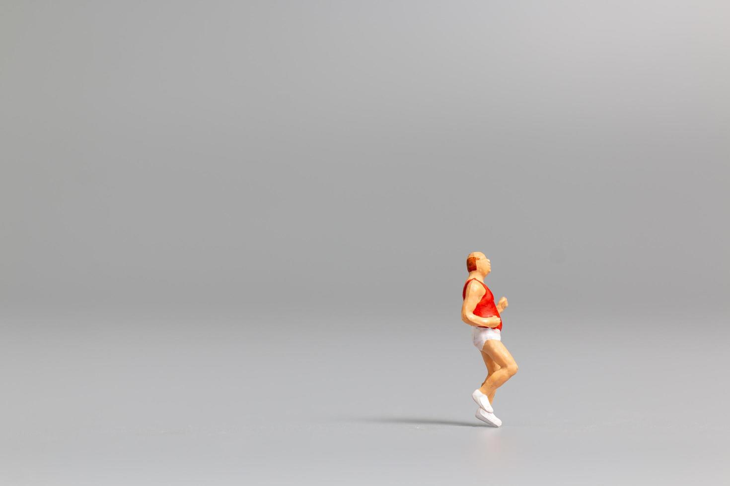 Miniature person running on a gray background photo