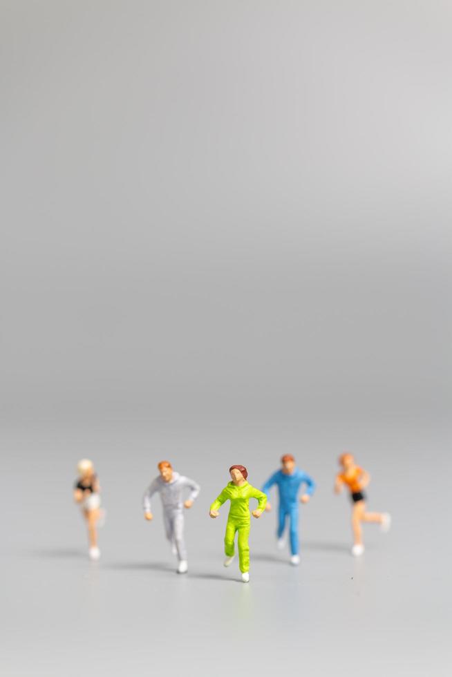 Gente en miniatura corriendo sobre un fondo gris foto