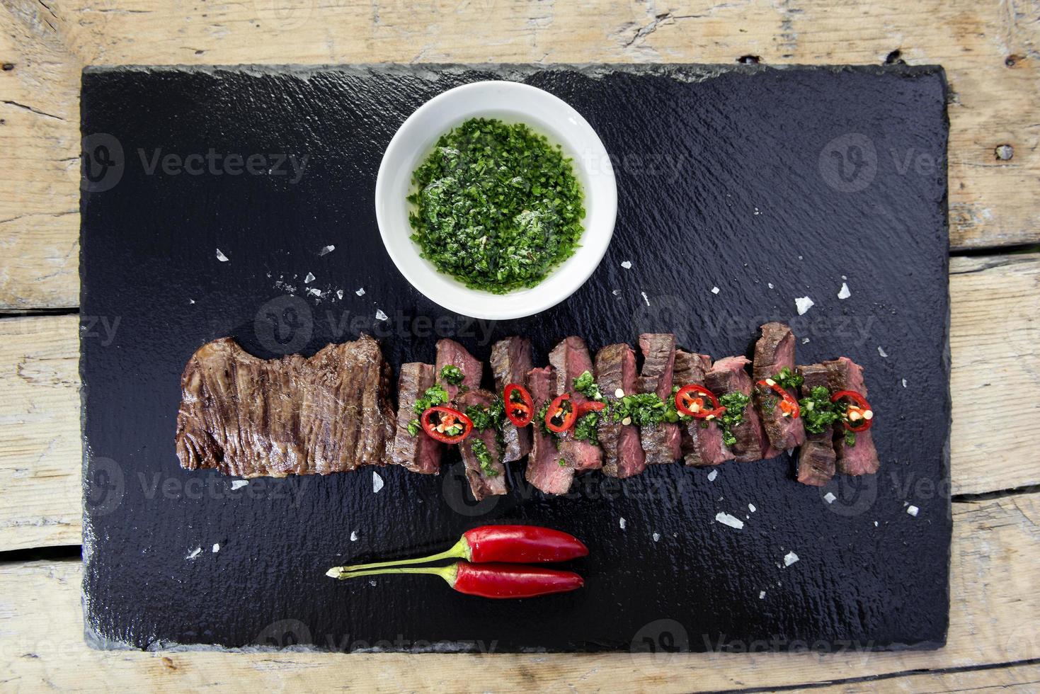 Plato de piedra negra con falda de bistec a la pimienta y salsa chimichurri foto