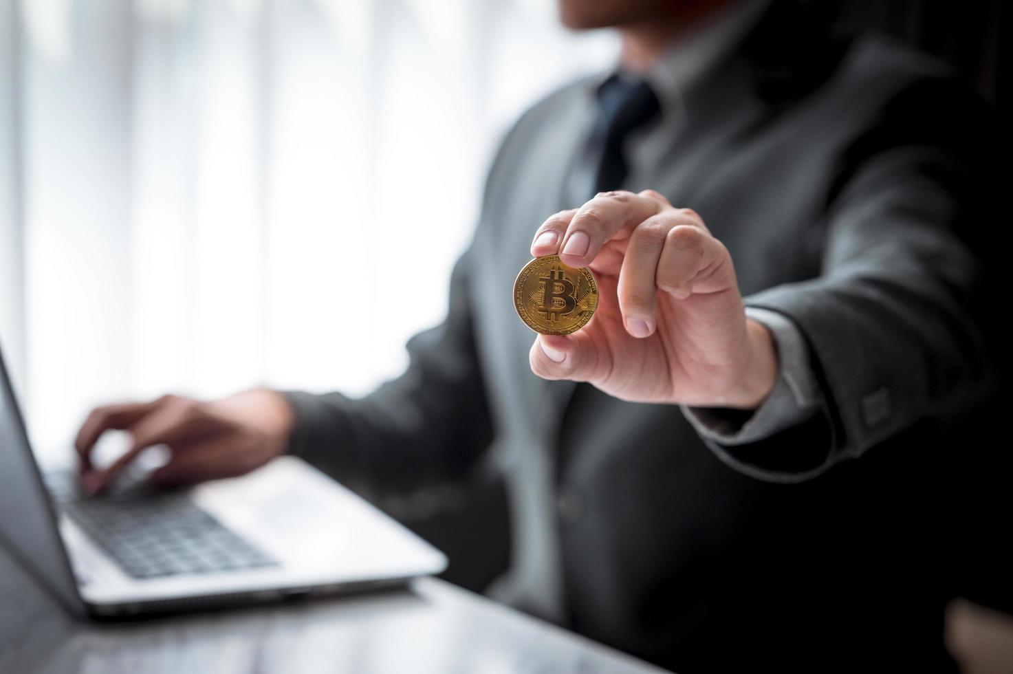 Businessman showing golden coins with bitcoin symbol photo