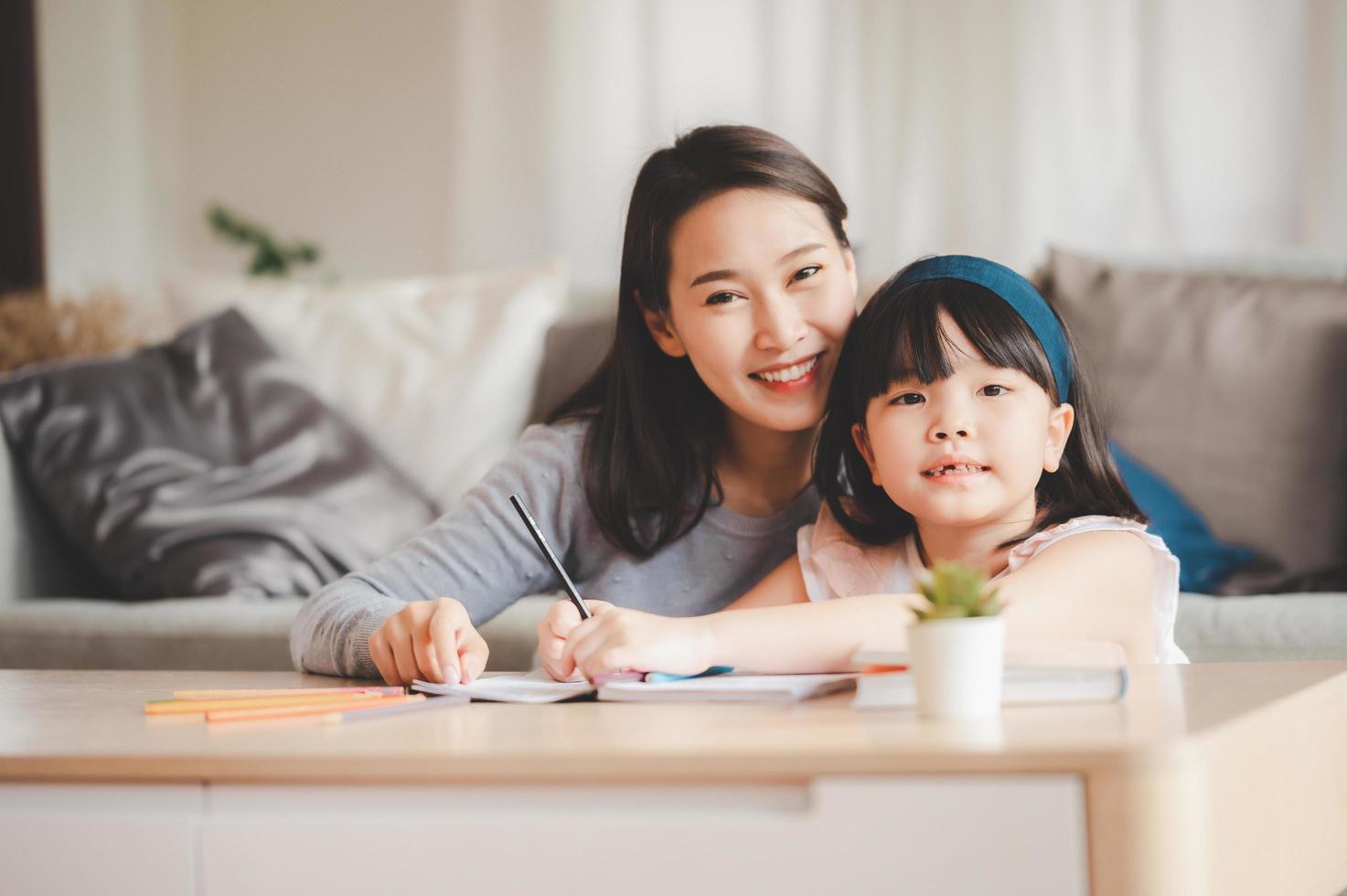 feliz madre de familia asiática e hija estudiando juntas foto
