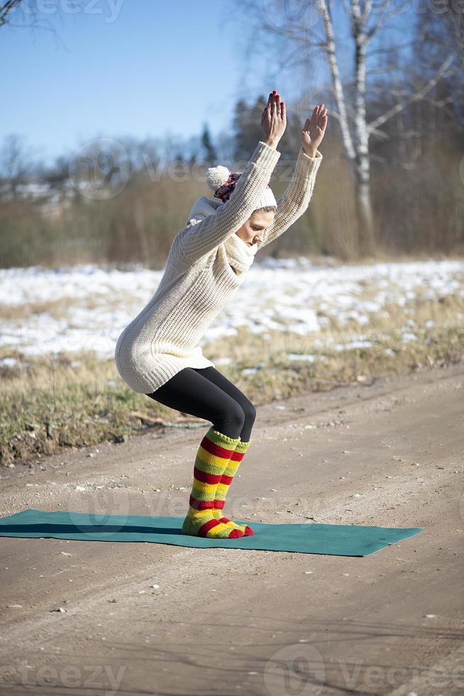 A young athletic woman performs yoga and meditation exercises outdoors photo