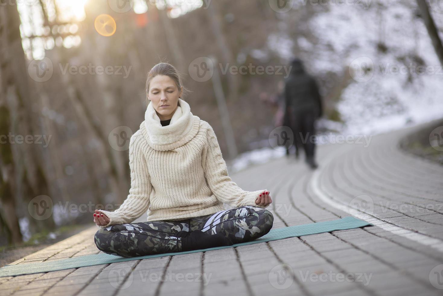 A young athletic woman performs yoga and meditation exercises outdoors photo