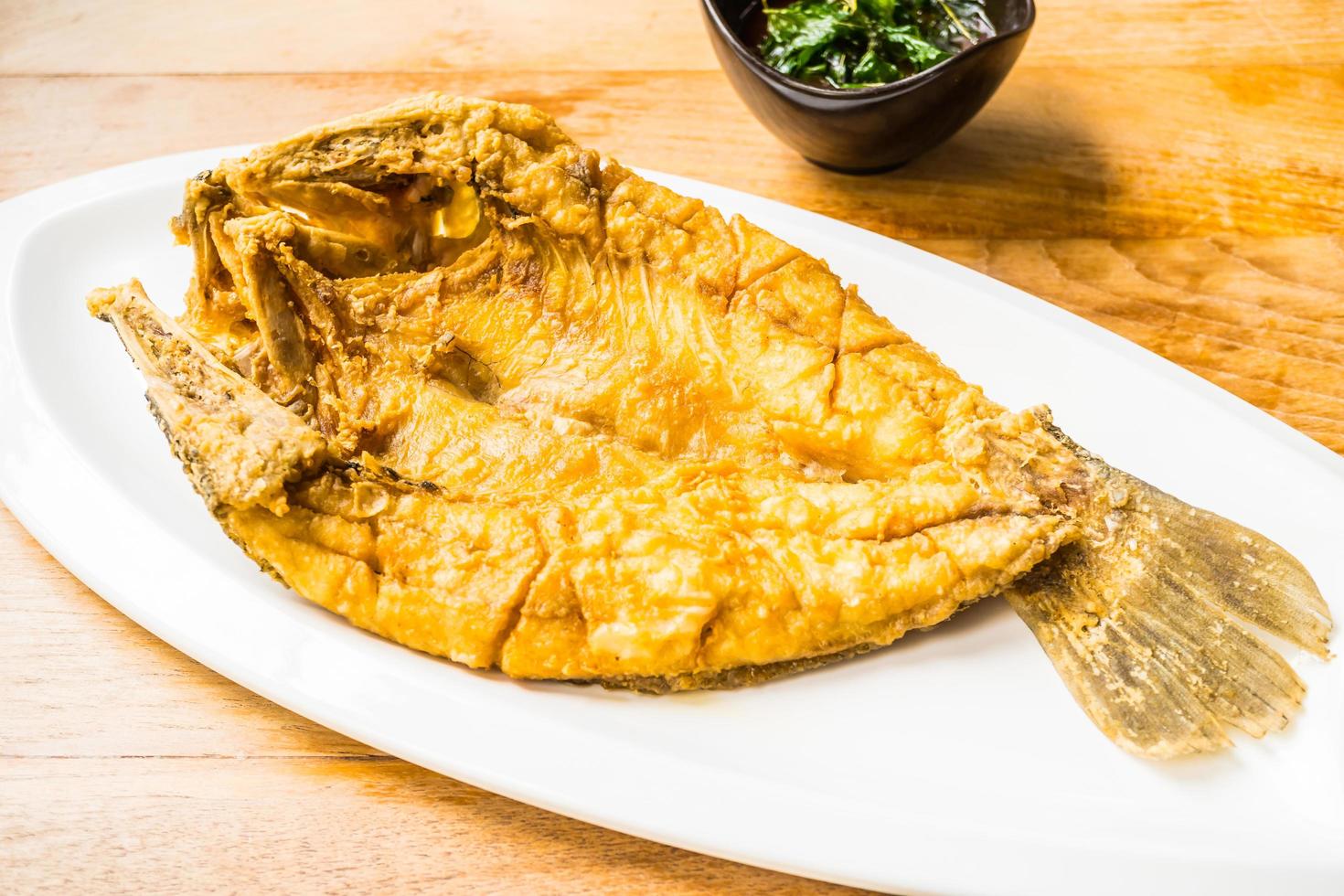 Pescado de lubina frito en un plato blanco foto