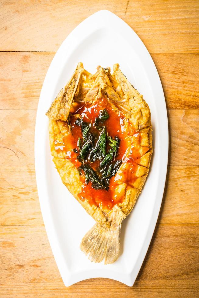 Fried sea bass fish in white plate with spicy and sweet sauce photo