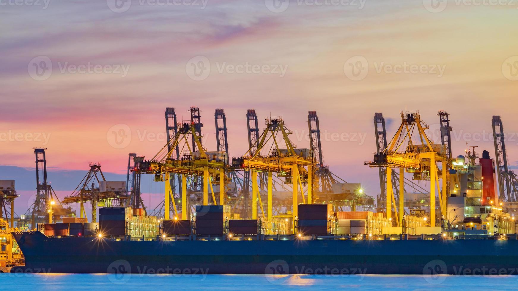 Freighter ship loading cargo at loading dock in Singapore at twilight photo