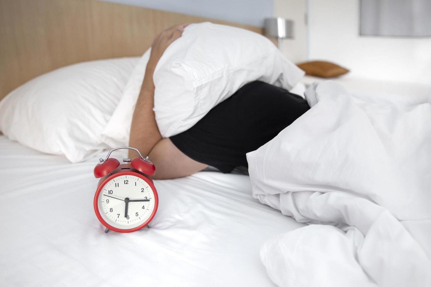 hombre siendo despertado por un reloj despertador foto