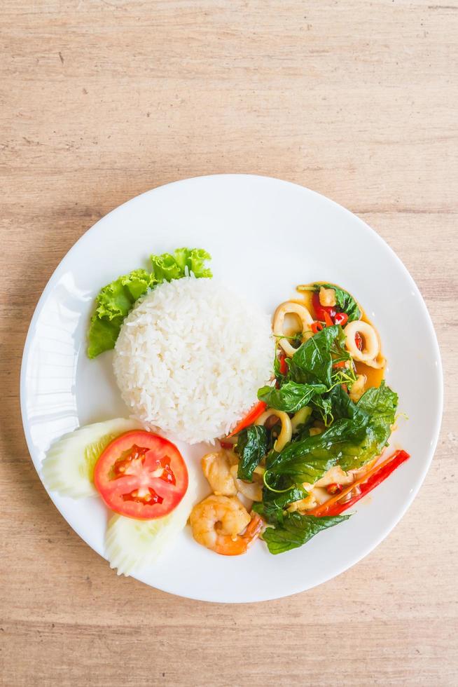 Spicy fried basil leaf with seafood and rice photo