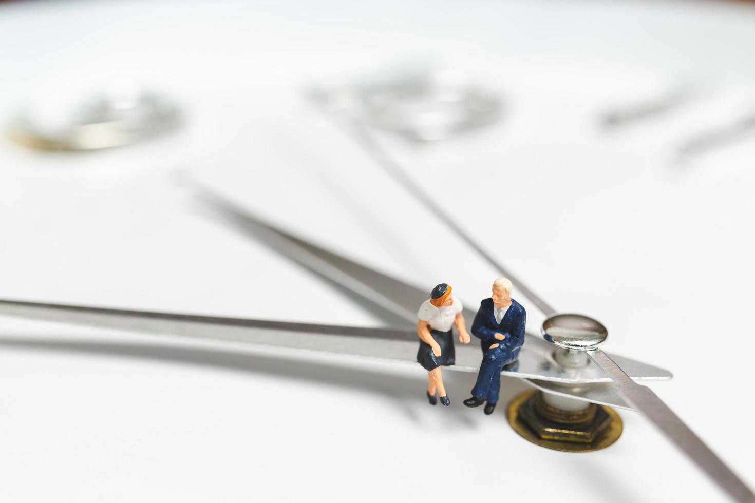 Miniature businesspeople sitting on a clock, concept of time and work photo