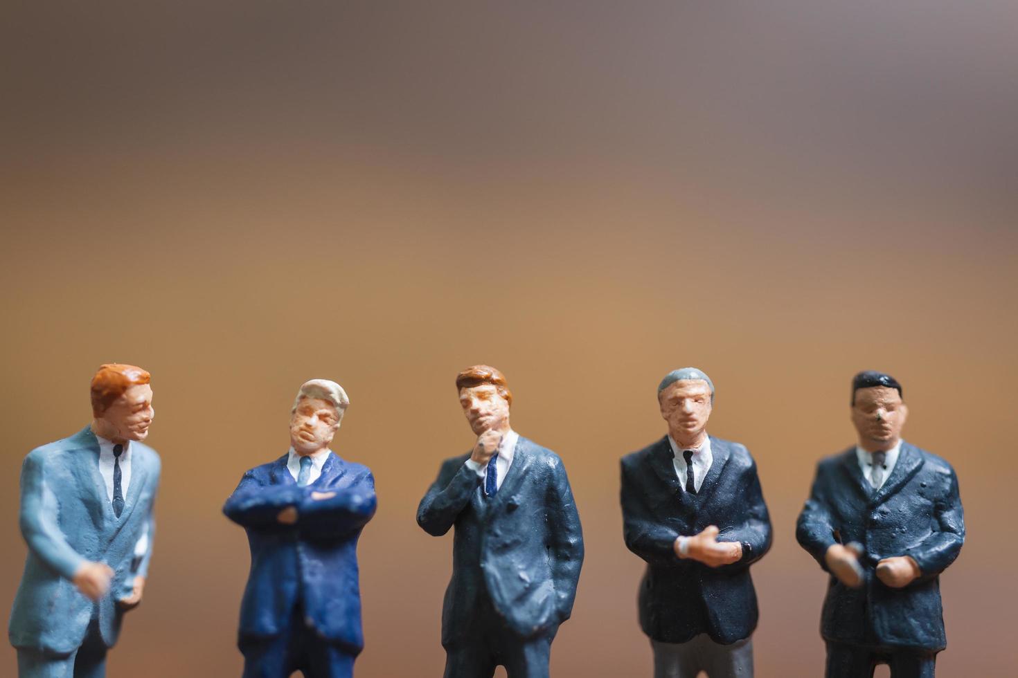 Miniature businessmen standing on a wooden background, business leader and teamwork concept photo