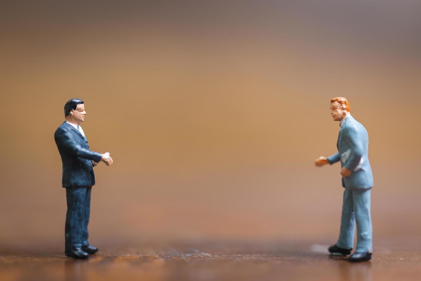 Miniature businessmen standing on a wooden background, business leader and teamwork concept photo