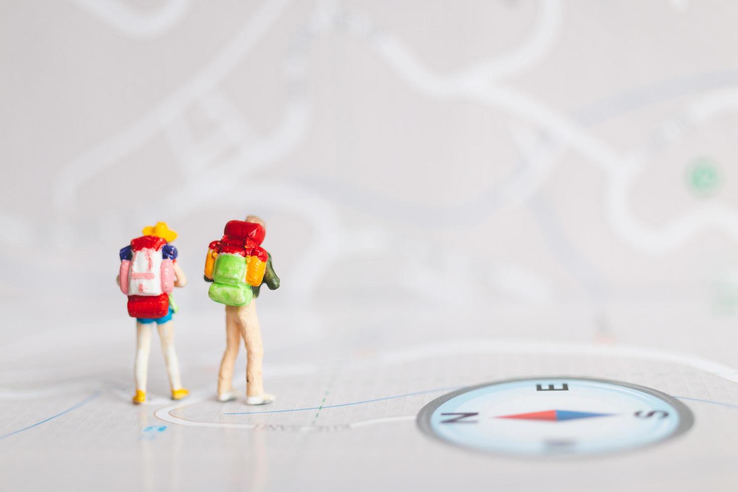 Miniature travelers with backpacks walking on a map, travel and adventure concept photo