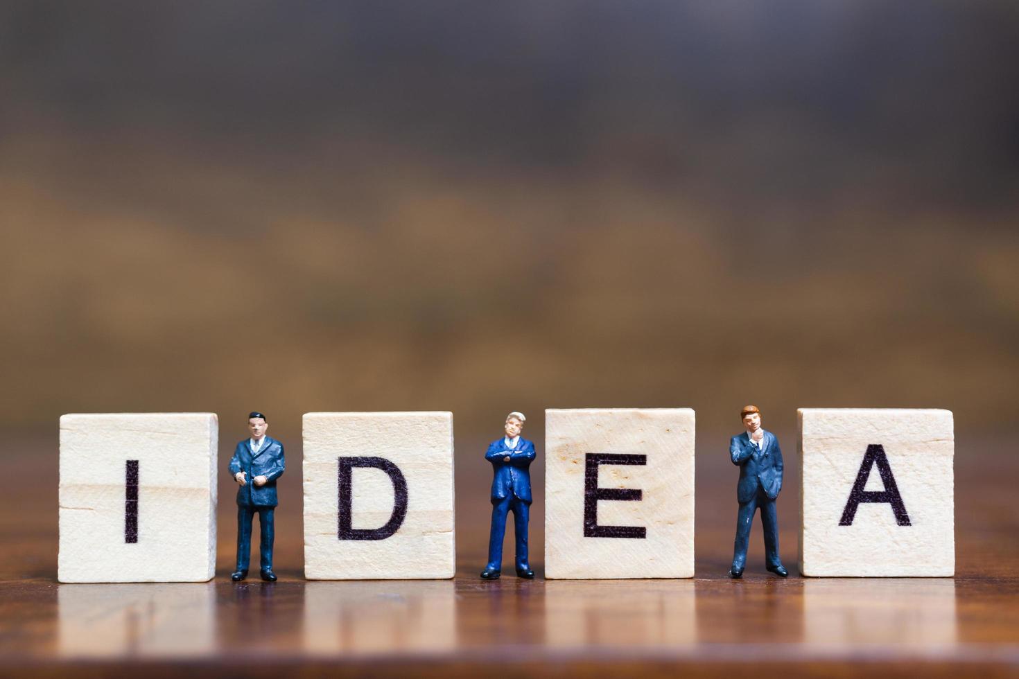 Miniature people standing with wooden blocks with the word Idea on a wooden background photo