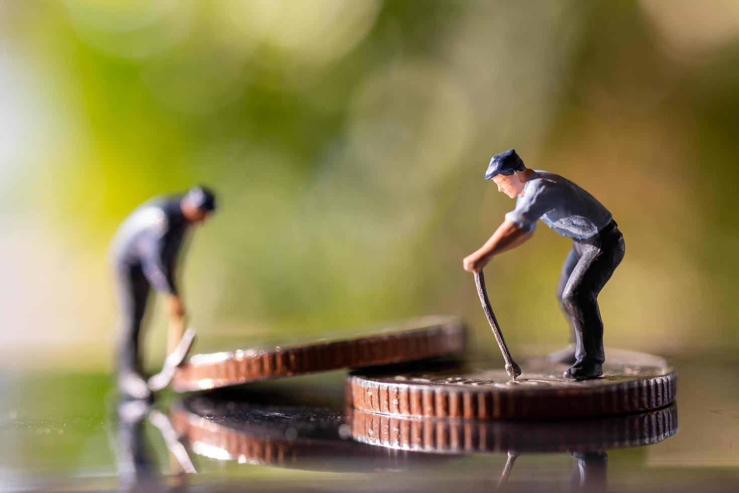 Trabajadores en miniatura sosteniendo herramientas en monedas con un fondo verde bokeh, concepto de construcción foto