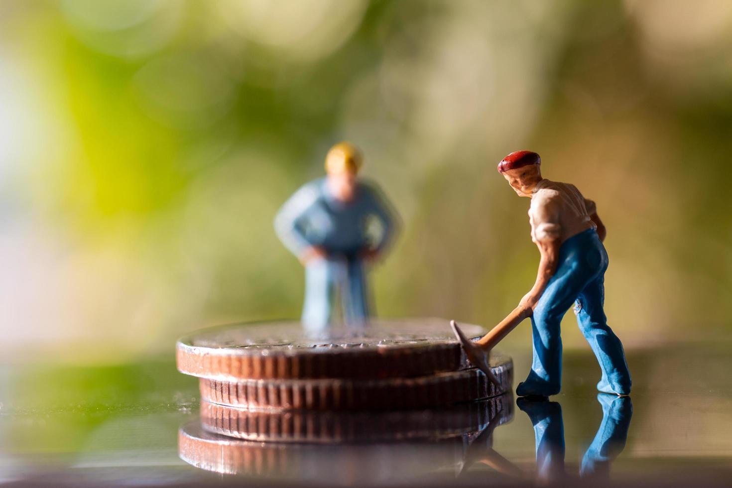 Trabajadores en miniatura sosteniendo herramientas en monedas con un fondo verde bokeh, concepto de construcción foto