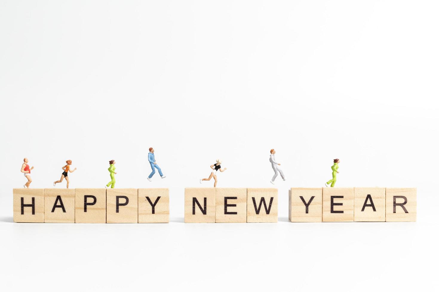 Miniature people running on wooden blocks with the text Happy New Year on a white background photo