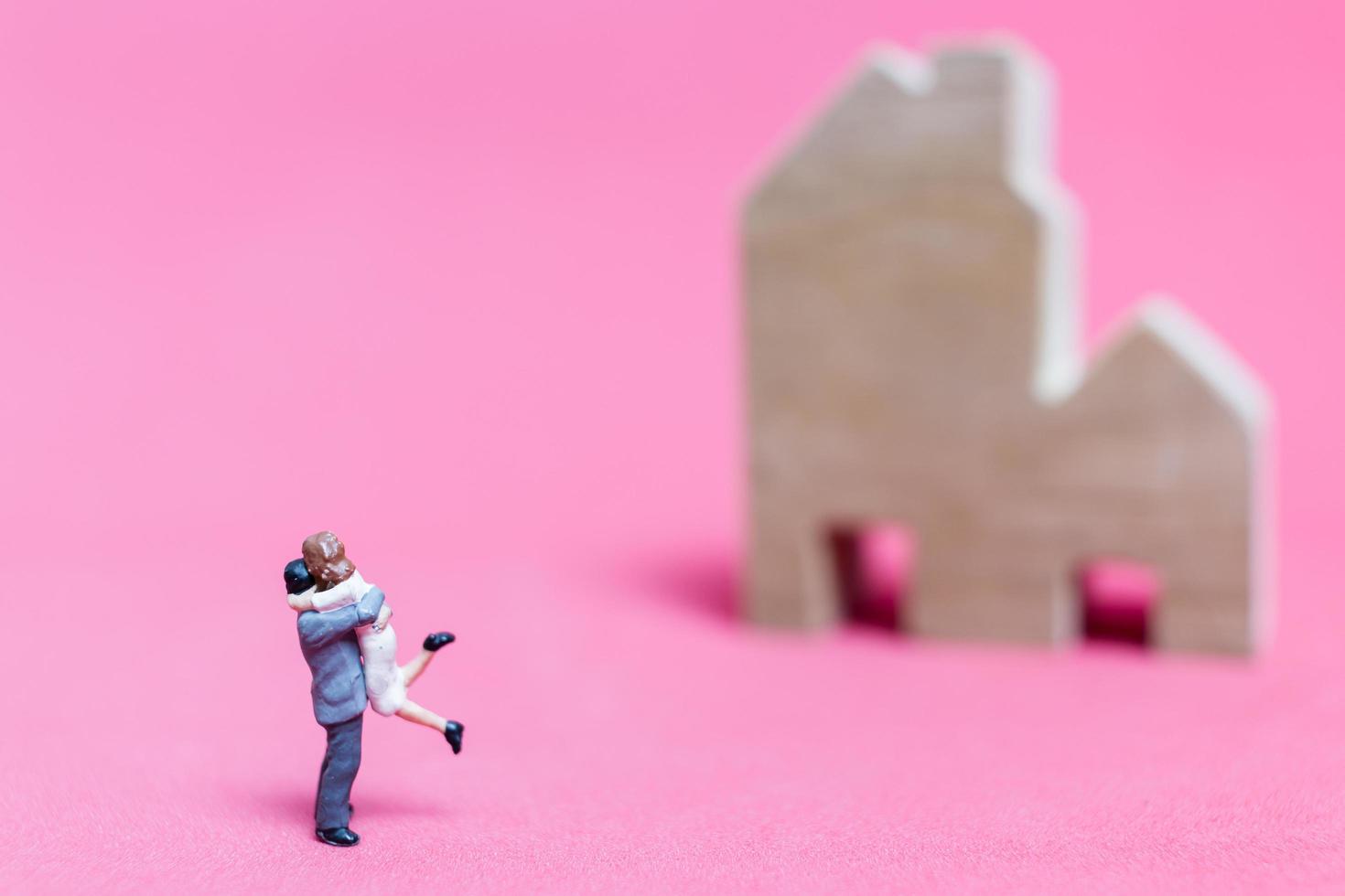 Miniature couple with houses on a pink background, Valentine's Day concept photo