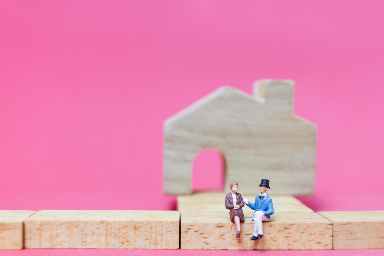 Miniature couple with houses on a pink background, Valentine's Day concept photo