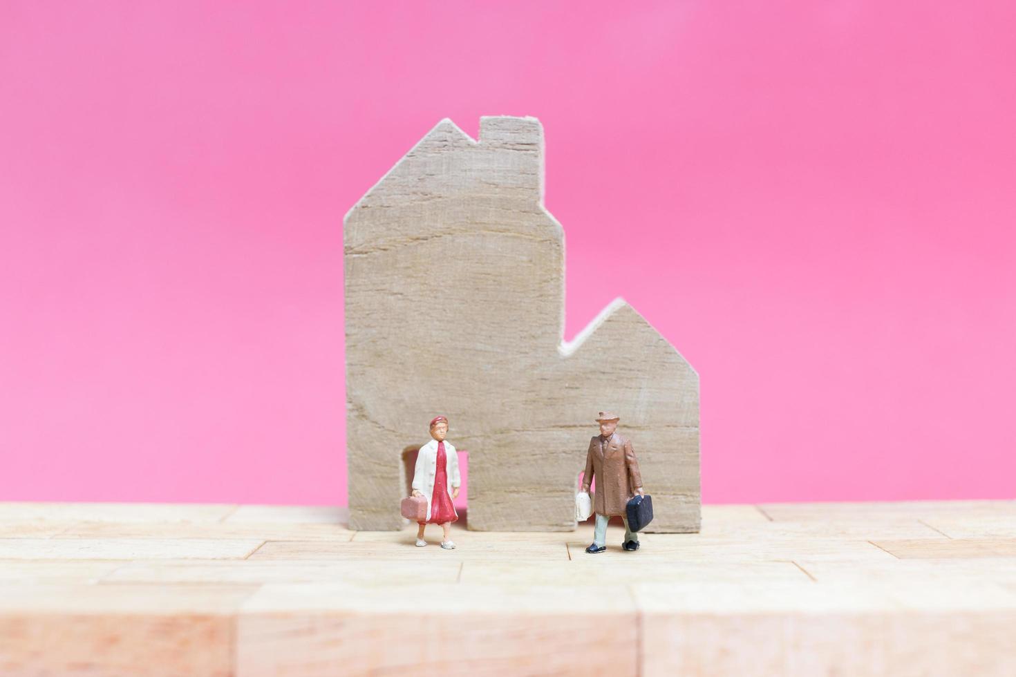 Pareja en miniatura con casas sobre un fondo rosa, concepto de día de San Valentín foto