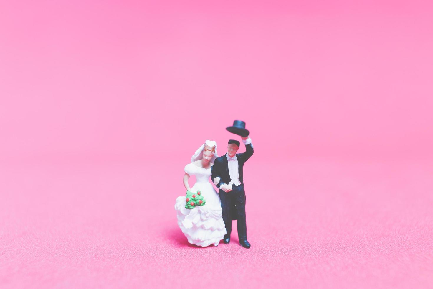 Boda en miniatura, una novia y el novio sobre un fondo de color rosa foto