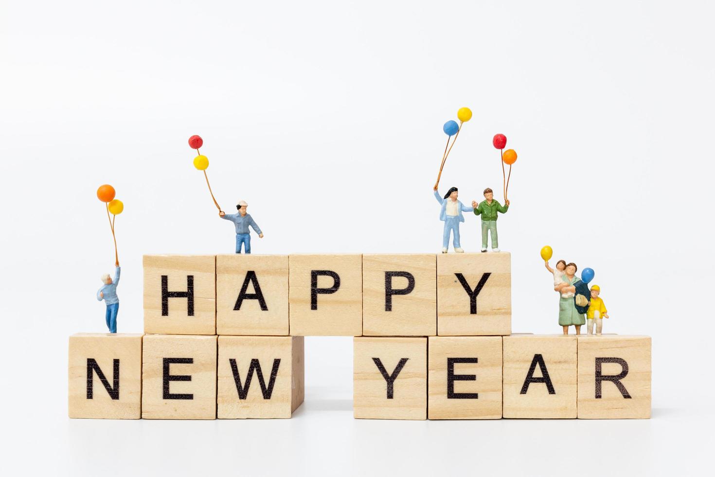 Familias en miniatura sobre bloques de madera con el texto feliz año nuevo sobre un fondo blanco. foto