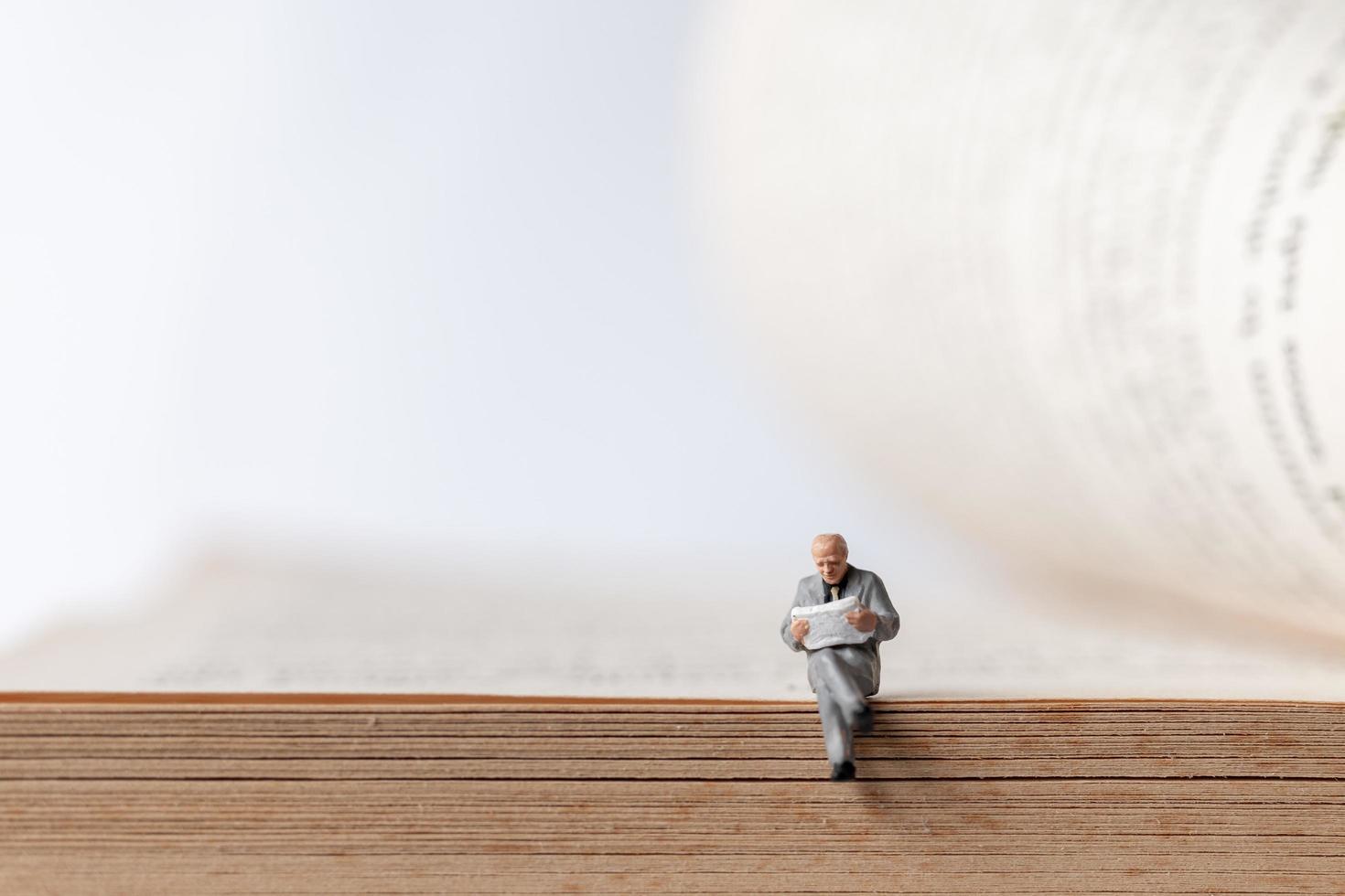 Miniature businessman reading a book on an old book, business education concept photo