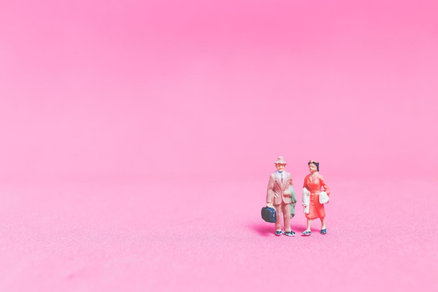Miniature couple of travelers on a pink background photo