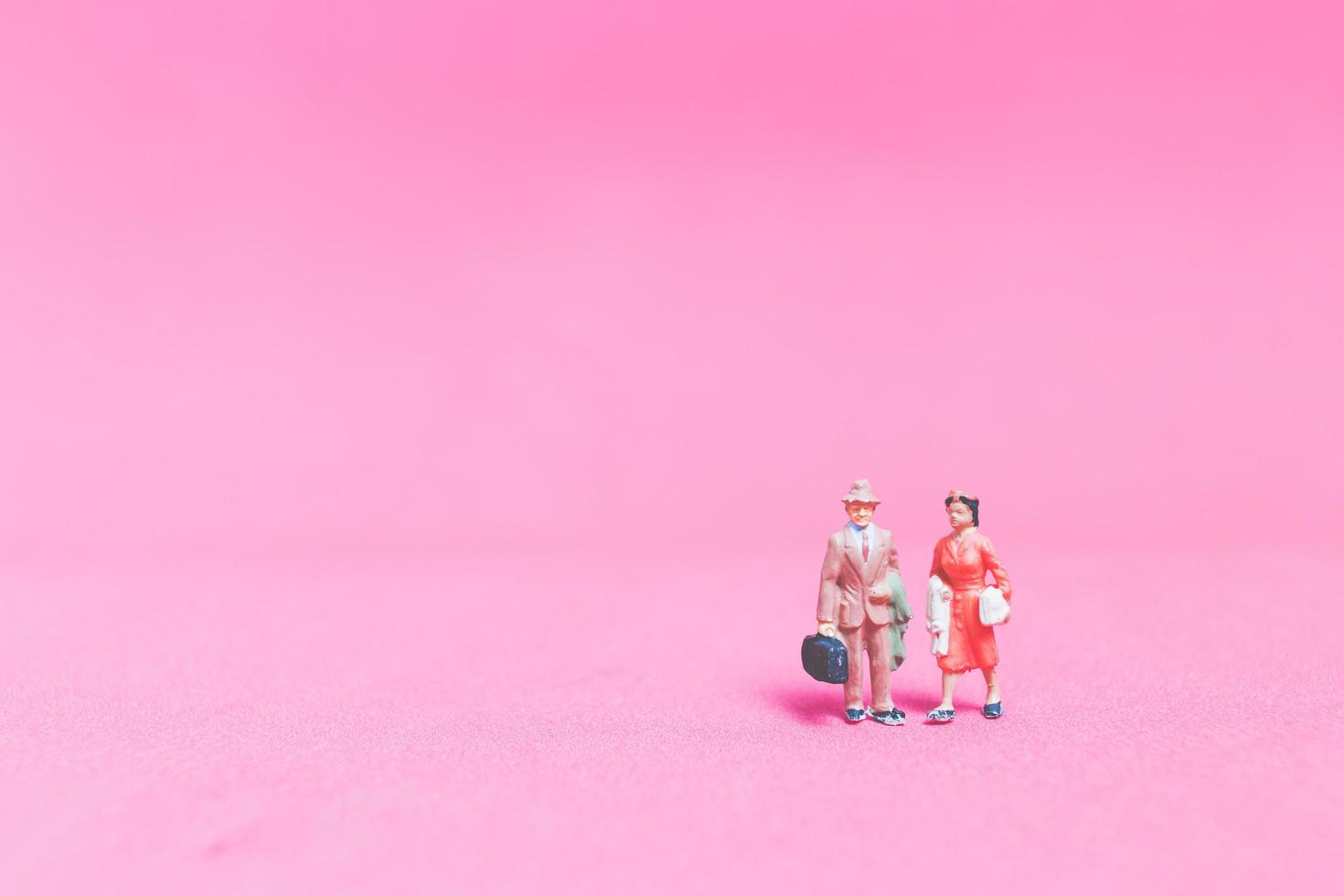 Pareja de viajeros en miniatura sobre un fondo de color rosa foto