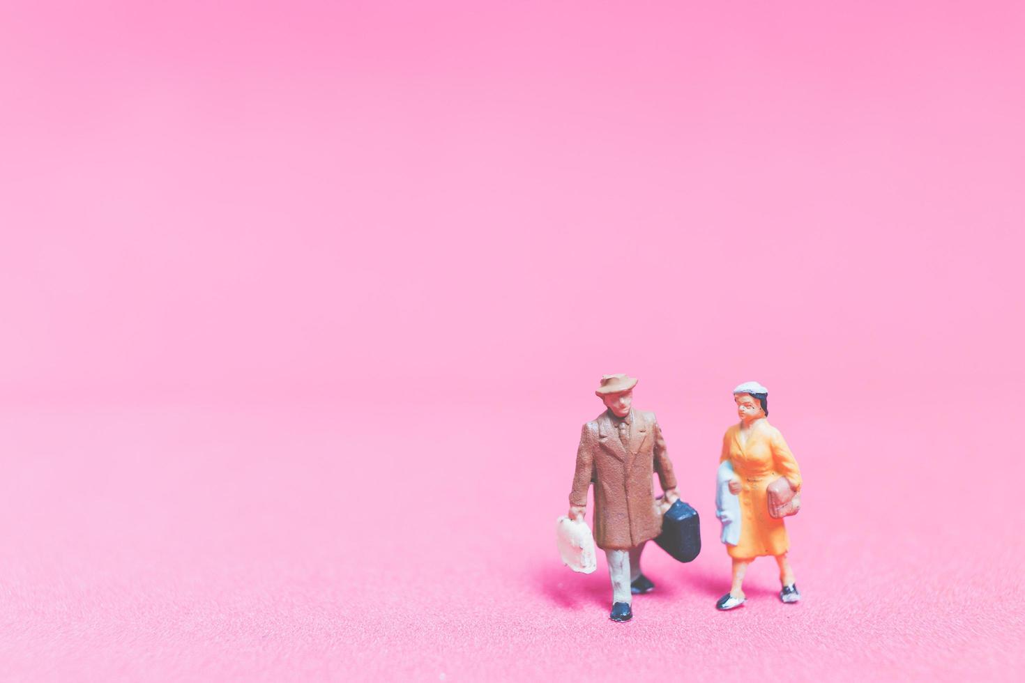 Pareja de viajeros en miniatura sobre un fondo de color rosa foto