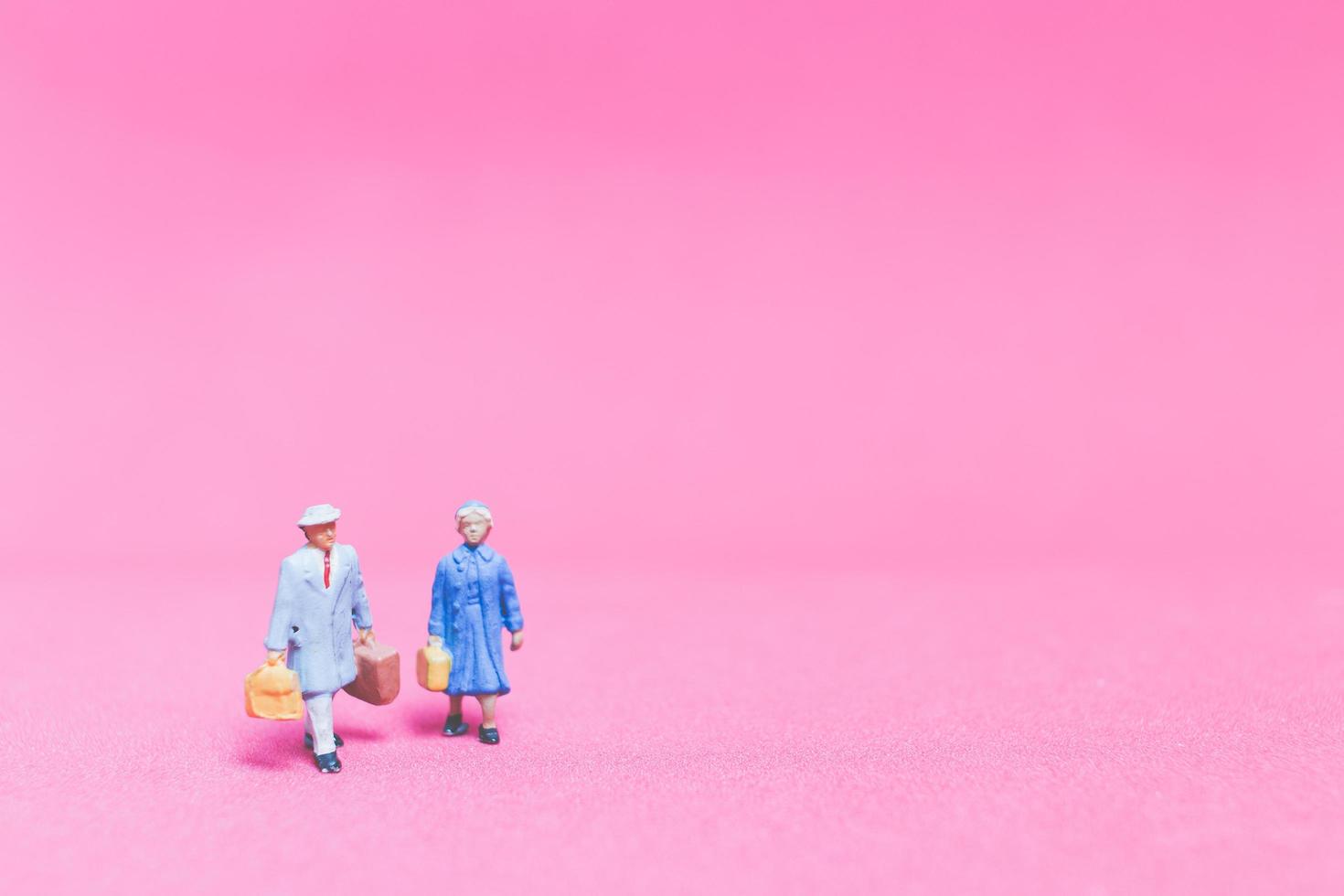 Miniature couple of travelers on a pink background photo