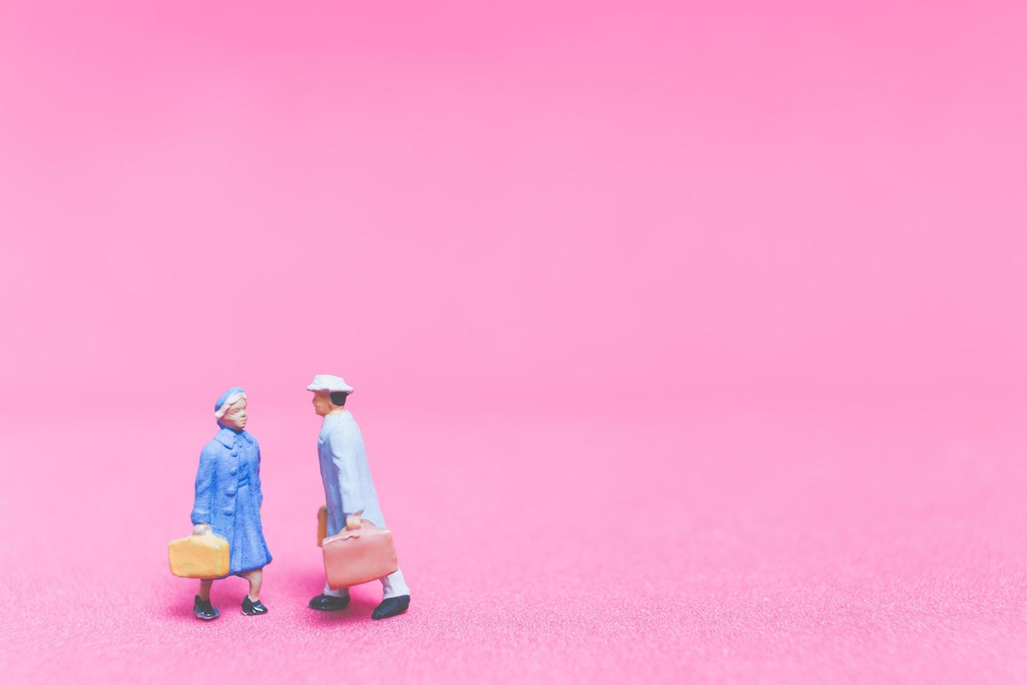 Pareja de viajeros en miniatura sobre un fondo de color rosa foto