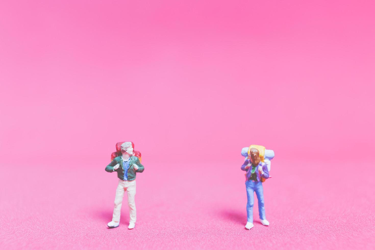 Pareja de viajeros en miniatura sobre un fondo de color rosa foto