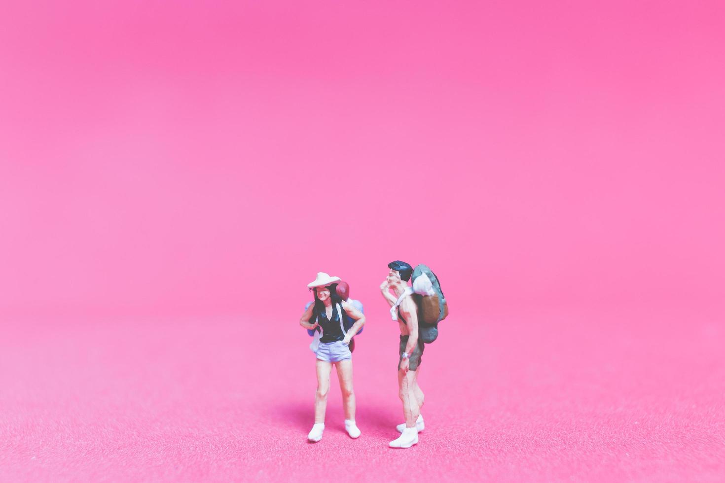 Miniature couple of travelers on a pink background photo