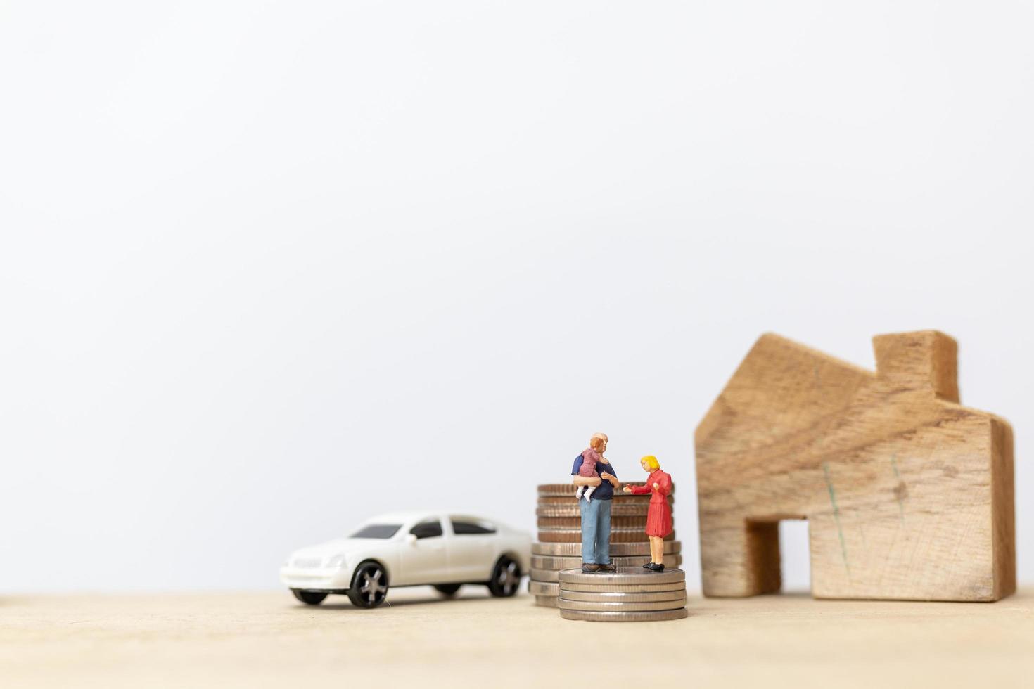Miniature parents and children with a house and a stack of coins, happy family concept photo