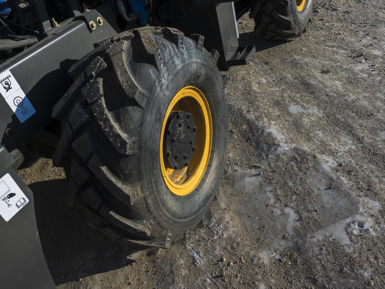 Close-up of a dirty loader wheel with a large tread and a yellow rim photo