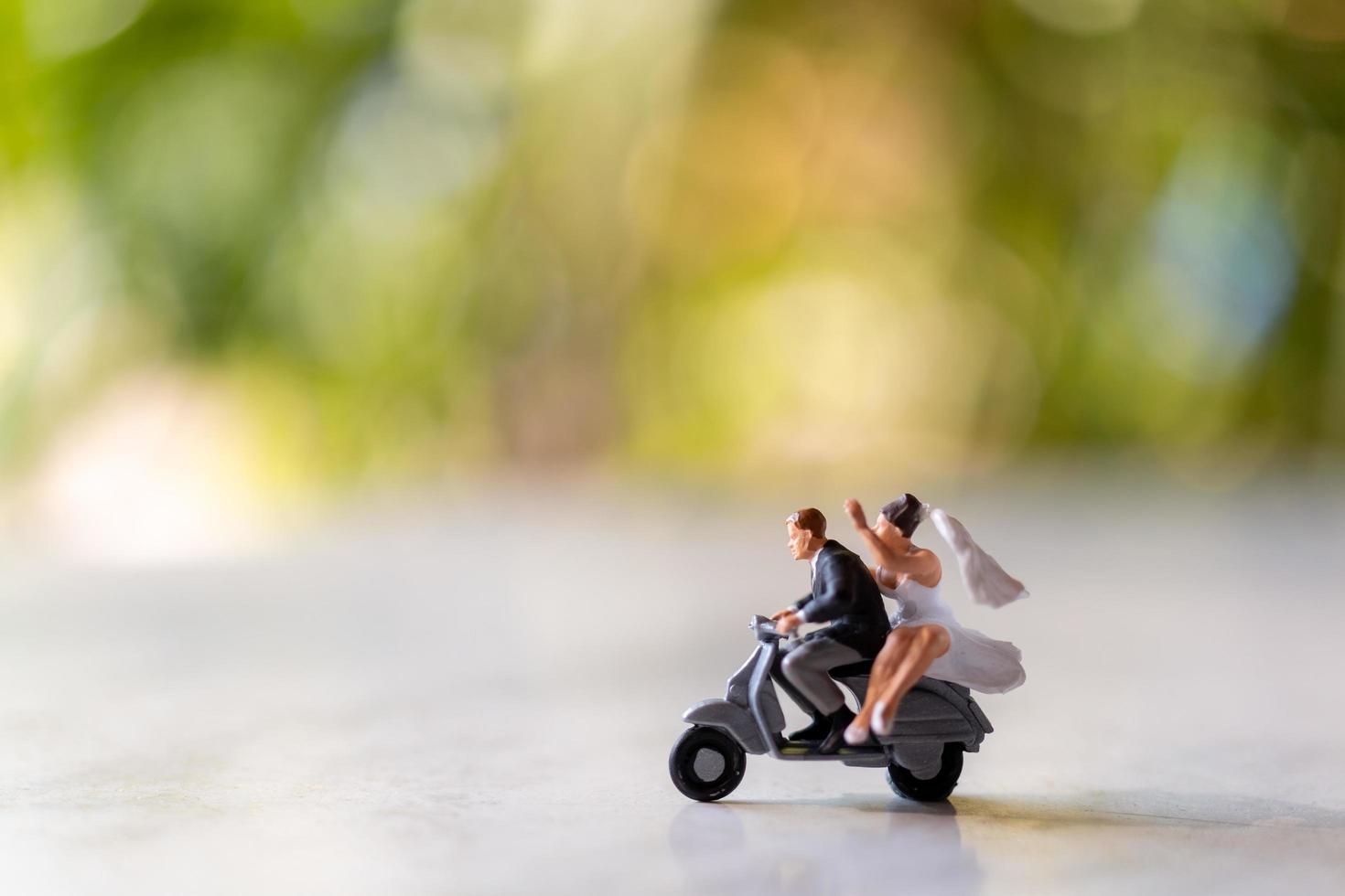 La novia y el novio en miniatura al aire libre con un fondo verde bokeh foto